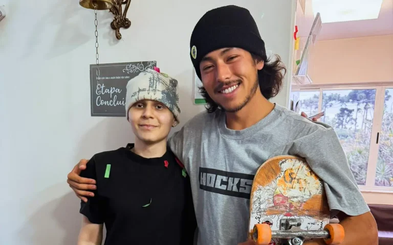 Jovem em remissão do sarcoma de Ewing abraçado a skatista, segurando skate, em ambiente de clínica oncológica em Curitiba